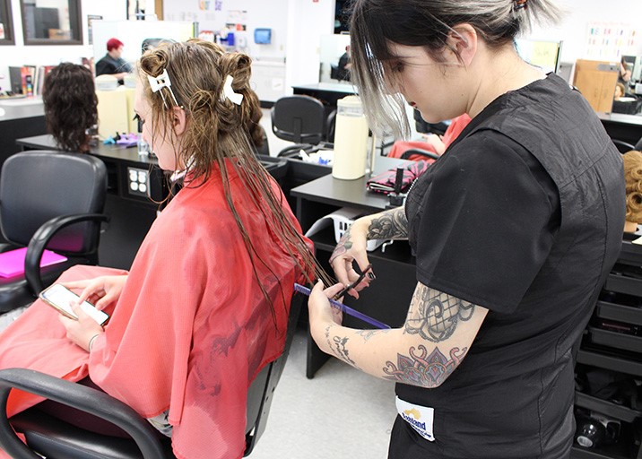 Cosmetology student cutting a customer's hair